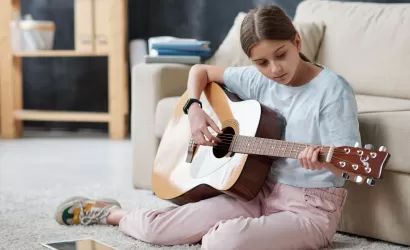 Niña tocando la guitarra en su habitación.