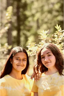 Dues noies somrient a càmera en un bosc