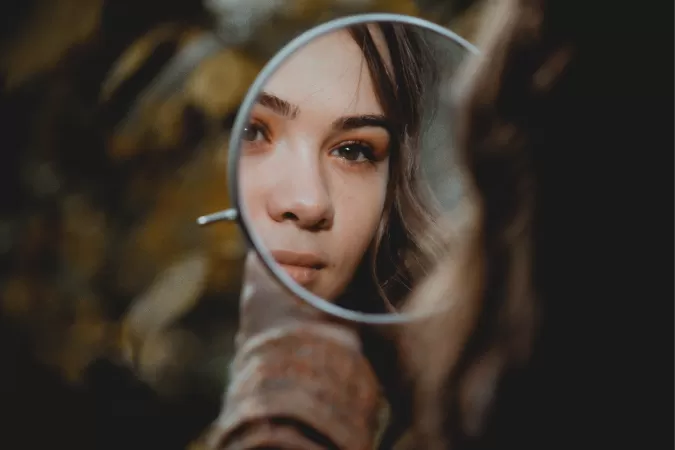 La cara d'una nena reflectida a un mirall de mà rodó